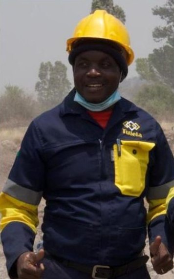 Smiling Tulela team member in hard hat and branded overalls on site